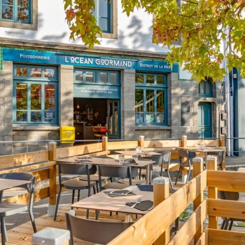a restaurant with tables and chairs in front of a building at Les apparts de Léon in Landerneau