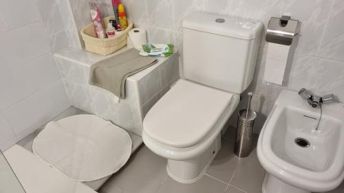 a bathroom with a white toilet and a sink at Hoyo 12 Islantilla in Huelva