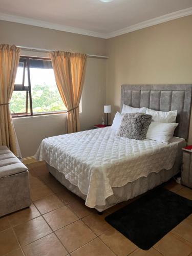 a bedroom with a large bed and a window at Ocean View Villas: Port Edward Unit H09 in Port Edward