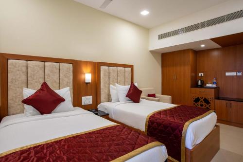 a hotel room with two beds with red pillows at HOTEL BLUEMOON in Tirunelveli