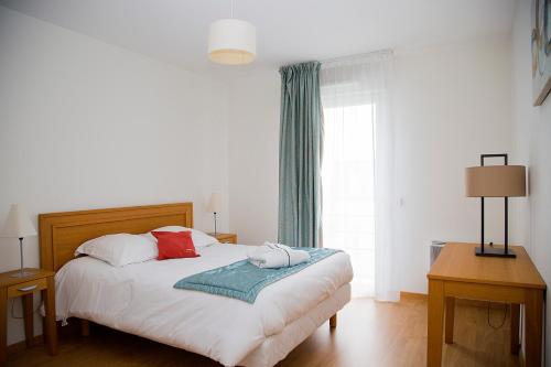 a bedroom with a bed with two pillows on it at Domitys Le Phare d'Argent in Cherbourg en Cotentin