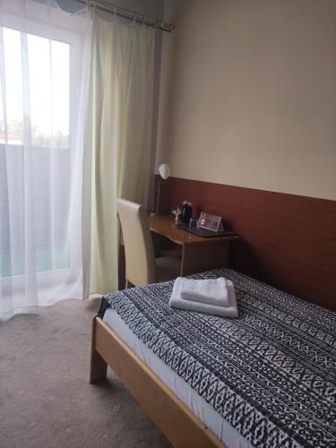 a bedroom with a bed and a desk and a window at Panoramic-Oscar in Mrągowo
