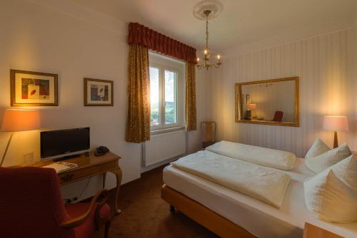 a bedroom with a bed and a desk with a computer at Flair Hotel Villa Ilske in Bad Kösen