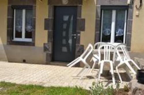 2 chaises blanches assises devant un bâtiment dans l'établissement maison de vacances Nébouzat, à Nébouzat
