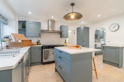 a kitchen with blue cabinets and white counter tops at Banbury Hill Farmhouse in Charlbury