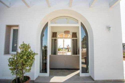 an arched doorway into a white house with a plant at Villa Rebecca in Porto Cesareo
