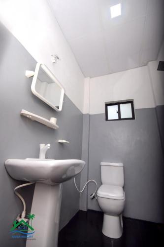 a bathroom with a sink and a toilet at ACH RIVER RESORT in Rattota