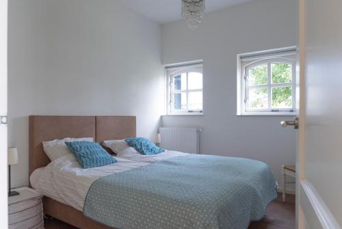 een witte slaapkamer met een bed met blauwe kussens bij De Dorsvloer in Drimmelen