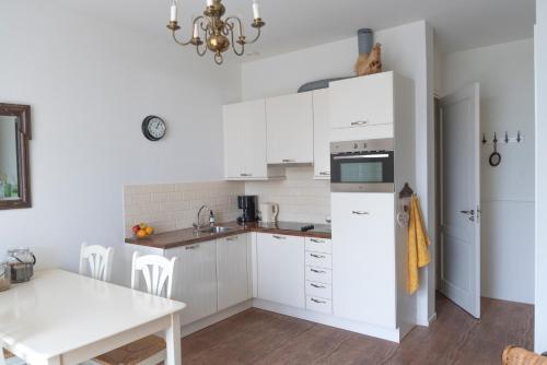 une cuisine avec des placards blancs et une table dans l'établissement De Dorsvloer, à Drimmelen