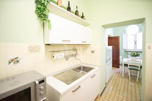 eine weiße Küche mit einem Waschbecken und einem Tisch in der Unterkunft Re Migio Apartment with Terrace and Lift in Lucca