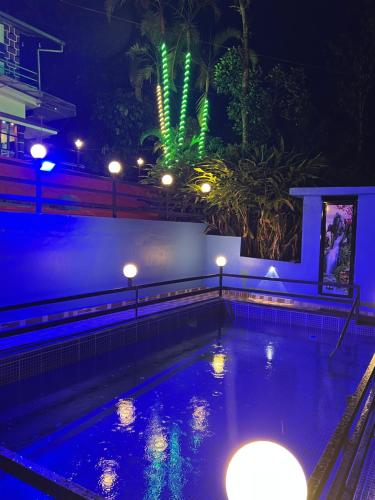 a swimming pool lit up at night with lights at ARABIAN HOLIDAY RESORT WITH SWIMMING POOL IN IDUKKI Calvary Mount in Idukki