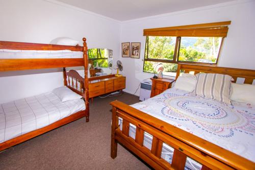 a bedroom with two bunk beds and a desk at Little Nikau - Tata Beach Holiday Home in Tata Beach