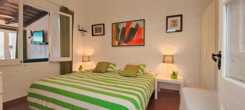een slaapkamer met een bed met een groen en wit gestreepte deken bij CASA CON JARDÍN A 35 METROS DE LA PLAYA. BR. in Palamós