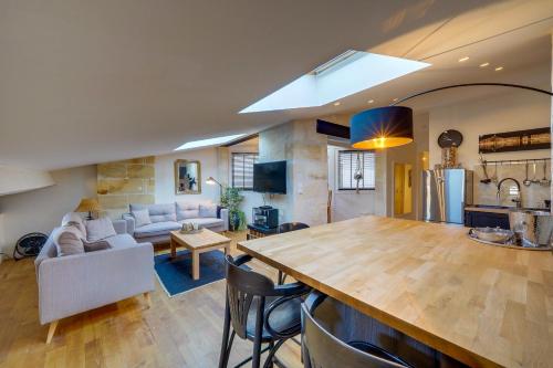 Il comprend une cuisine et un salon avec une grande table en bois. dans l'établissement Le Mansardé - Bail Mobilité Agréable et calme en plein centre, à Bordeaux