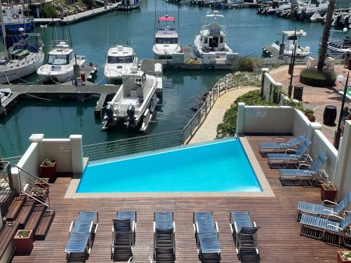 a swimming pool on a deck with boats in a marina at Port Edge - Ships Bell, Port St Francis Bay in St Francis Bay