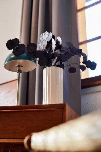 a white vase with flowers in it next to a lamp at pop-up stuub feldberg in Feldberg