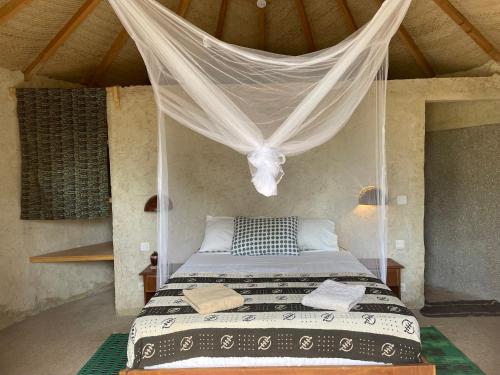 a bedroom with a bed with a mosquito net at Bégué Lodge in Dinouar