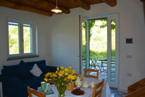 uma sala de estar com uma mesa com flores e um sofá em Casale Dionisia a Castellabate, Appartamento Fico em Santa Maria di Castellabate