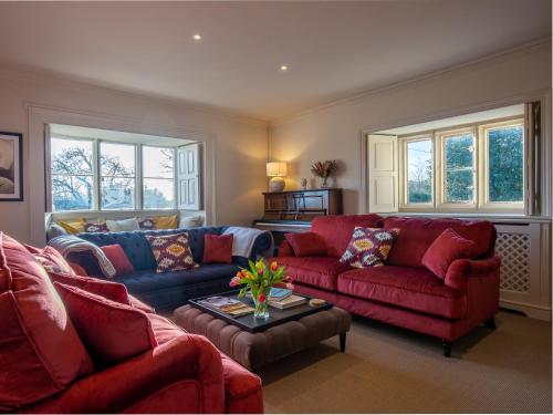 a living room with two red couches and a table at Green Farm House in Cirencester