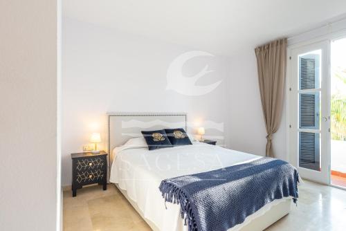 a white bedroom with a bed and a window at Jardines de las Golondrinas in Marbella