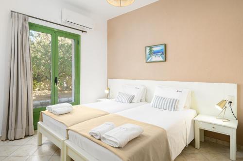 een slaapkamer met 2 bedden met witte lakens en een raam bij Villa Vicky in Chersonissos