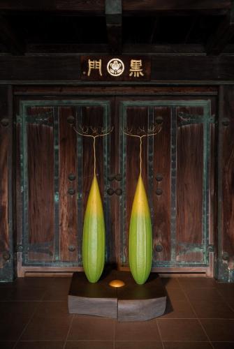 two green and yellow vases in front of a wooden wall at Ichiraku tendo spa & brewery in Tendo