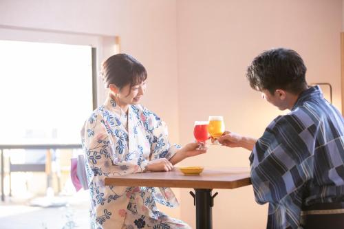 a man and woman sitting at a table drinking orange juice at Ichiraku tendo spa & brewery in Tendo