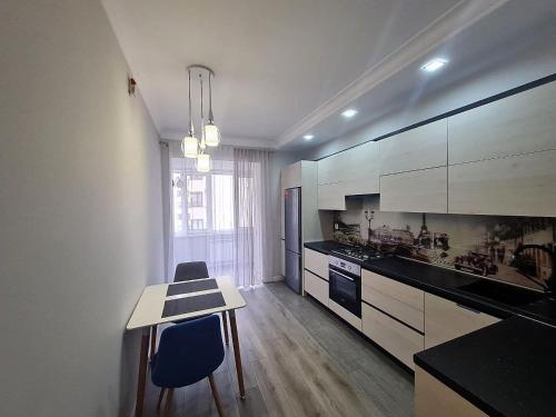 a kitchen with white cabinets and a table and chairs at Apartament, sectorul Buiucani in Chişinău