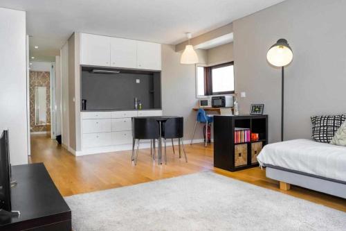 a living room with a bed and a kitchen with a television at Póvoa Beach Apartment in Póvoa de Varzim
