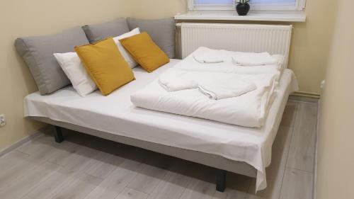 a white bed with yellow pillows on top of it at Apartament Szczawno-Zdrój -Wałbrzych in Wałbrzych