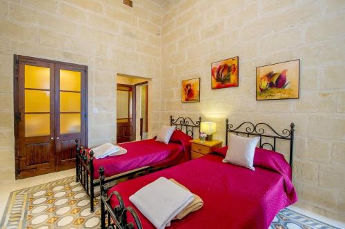2 posti letto in una camera con lenzuola rosse di Ta Gananz Holiday Home a Għasri