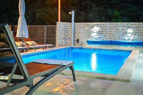 uma piscina com uma cadeira e um guarda-sol em Villa Sierra em Sinj