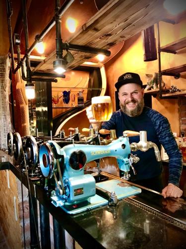 a man is standing behind a sewing machine at HARABURDI® Recyclart Hotel in Kostelec nad Orlicí