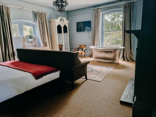 um quarto com uma cama, uma cadeira e uma banheira em Verzon House em Ledbury