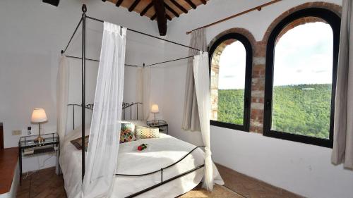 a bedroom with a canopy bed and two windows at Case Domine in Radda in Chianti