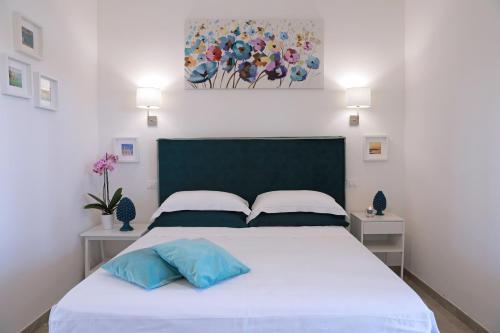 a bedroom with a white bed with two blue pillows at Tenuta Cesarina in Alessano