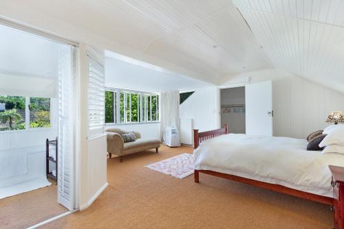 a white bedroom with a bed and a chair at Craiglea Newlands - Villa with Pool & Tennis Court in Cape Town