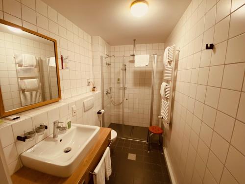 a white bathroom with a sink and a shower at Hotel Hartl's Lindenmühle in Bad Berneck im Fichtelgebirge