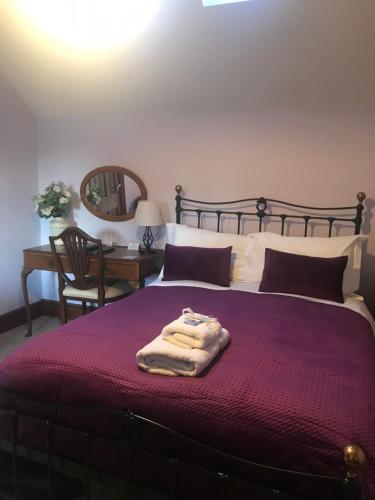 a bedroom with a large bed with a purple blanket at The Post House in Ibstock