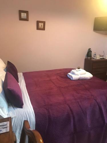 a bedroom with a purple bed with two towels on it at The Post House in Ibstock
