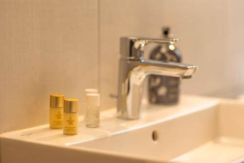 a bathroom sink with a faucet and three products on it at Familiengasthof Schaller in Floß