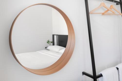 CASA BLANCA Dusit في Dusit: مرآة مستديرة في غرفة بيضاء مع سرير