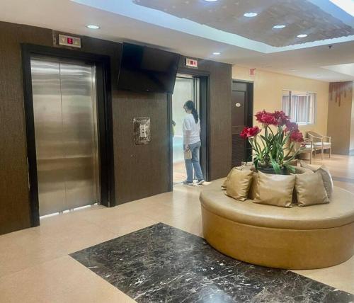 a woman standing in a lobby with a round couch at Condominium Suites at Chateau Elysee - Ritz in Manila