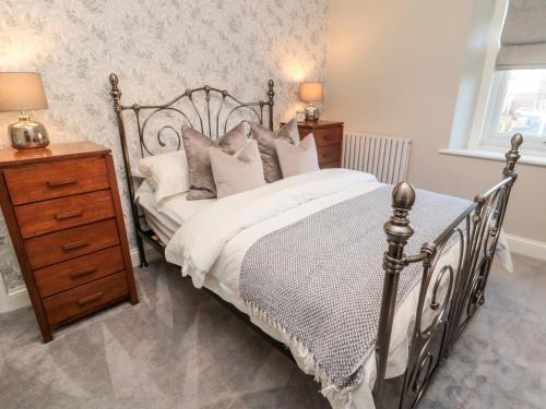 ein Schlafzimmer mit einem Metallbett mit Kissen und einer Kommode in der Unterkunft Mulberry House in Morpeth