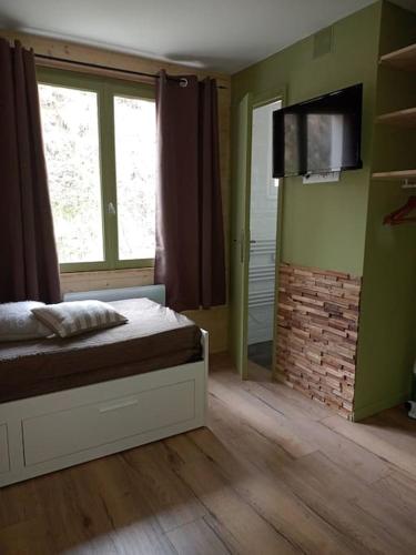une chambre avec un lit et une télévision au mur dans l'établissement RÉSIDENCE LE SÉNÉOU, à Les Deux Alpes