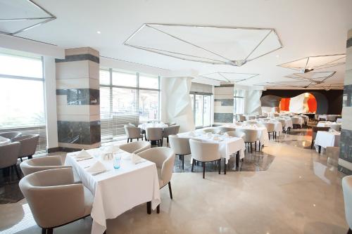 a restaurant with white tables and chairs and windows at Elexus Hotel Resort & Spa & Casino in Kérynia