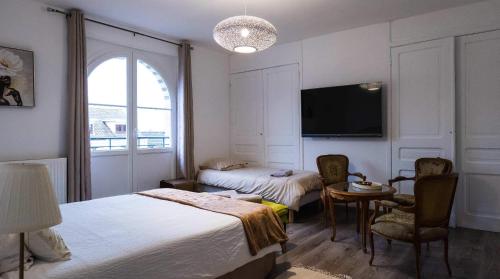 um quarto de hotel com duas camas e uma mesa e uma televisão em A La Villa Perroy les chambres sont spacieuses et les petit-déjeuners offerts em Dunkerque