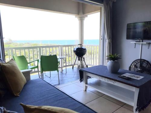 d'un salon avec une table et un balcon. dans l'établissement Izinyoni Place, Mangrove Beach Estate, à Port Shepstone