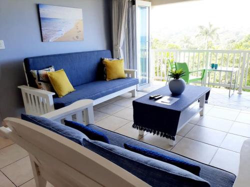 - un salon avec un canapé bleu et une table dans l'établissement Izinyoni Place, Mangrove Beach Estate, à Port Shepstone
