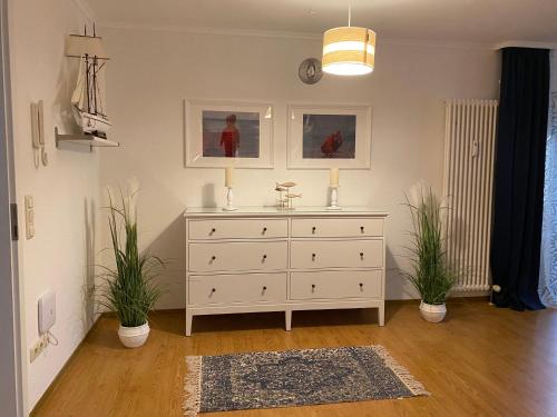 a white dresser in a room with two plants at Appartementanlage Ostseeblick in Kühlungsborn